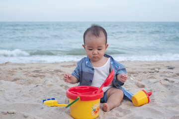 Adorable Cute Asian baby boy playing with beach toys on tropical beach