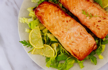 Grilled salmon with salad served on gray plate.