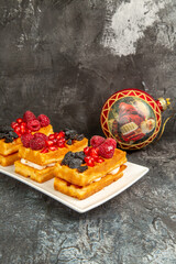 front view waffles with berries on white rectangular plate xmas tree ball on dark background with copy space