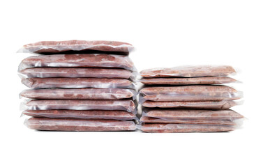Frozen ground meat packages in stacks with backs, necks, liver and heart. Left chicken, right turkey. Concept for raw food diet for pets. Or chicken versus turkey for cats or dogs. Selective focus.