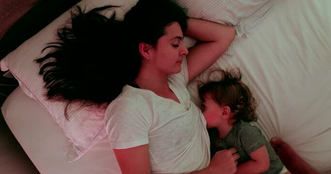 Mother breastfeeding in bed at night, top view