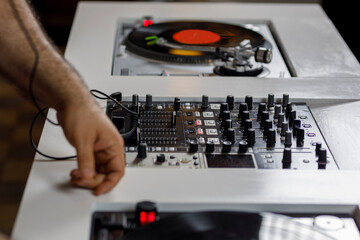 Mesa de Dj con un tocadiscos que tiene un disco de vinil rosa y unos audífonos al costado....
