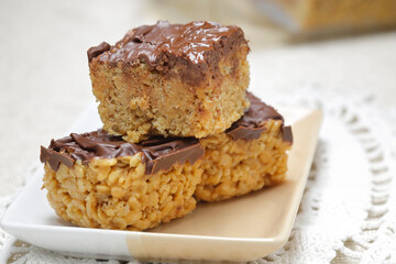 A close up of three rice krispie treats on a plate.