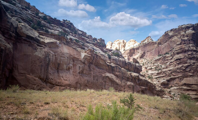 Unbelievable sandstone cliff and superlative domes with tumbleweeds on a hot summer partly cloudy day in Capitol Reef National Park in Southern Utah