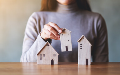 Closeup image of a woman holding wooden house models on the table