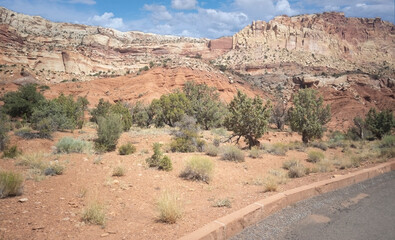 Unbelievable sandstone cliff and superlative domes with tumbleweeds on a hot summer partly cloudy day in Capitol Reef National Park in Southern Utah