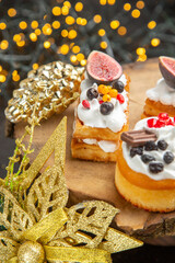 front view delicious cream cakes around new year tree toys on the dark background dessert cake sweet photo cream