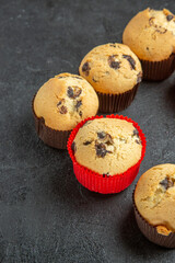 Vertical view of freshly baked delicious small cupcakes with chocolates on dark background