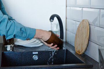 a woman washes dishes. washing the cup in the black sink