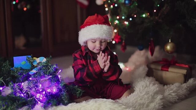 a child in red clothes is sitting waiting for the new year. the concept of celebrating Christmas at midnight. holiday costume