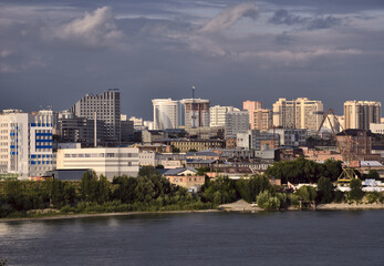 The modern buildings of the big city is illuminated by the bright sun against the cloudy sky