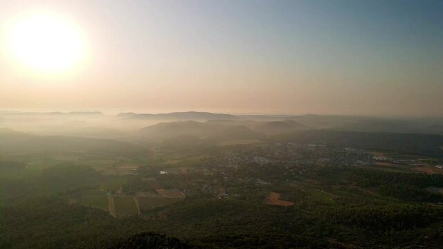 Take from a drone the village of Saint Mathie de Treviers, accompanied by a low fog in the early morning.
