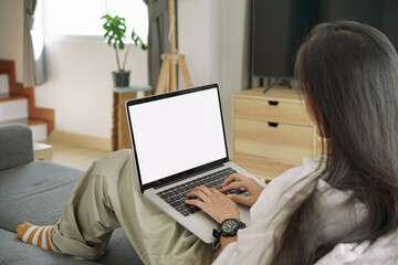 Fototapeta premium Side View shot of young business woman working with mockup white screen laptop computer in living room at her home. Working at home concept