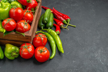 Half shot of fresh vegetables inside and outside of a brown wooden basket on the right side on dark background