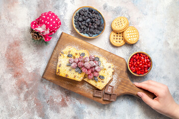 top view raisin cake on cutting board in woman hand bowl with pomegranate a bowl of raisins biscuits on marble ground with copy space