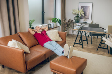 Grey-haired man sitting on the sofa and resting