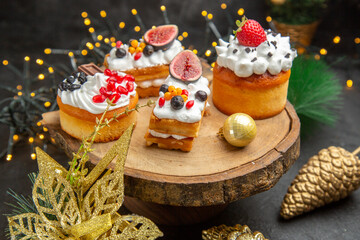front view delicious cream cakes around new year tree toys on dark desk cake sweet photo cream dessert