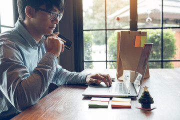 Asian man holding credit card and typing keyboard on laptop with shopping online.