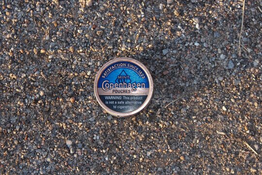 Copenhagen Mint chewing Tobacco shot closeup sitting on rocks that's bright and colorful.