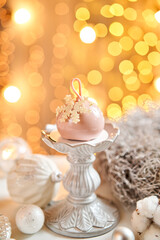 Fototapeta na wymiar Mini mousse pastry dessert with pink glazed. Garland lamps bokeh on background. Modern european cake. French cuisine. Christmas theme. Snowflake