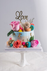 Wedding cake with pink rose and colorful macaroon on white table and white background,Love and wedding concept decoration