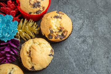 Above view of new year decorations around small cupcakes with chocolates on dark background