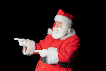 Santa Claus shows with his hands to the side on blank space isolated on black background. Santa urges to point to Copyspace.