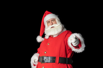 Cheeky old man with a gray beard in a Santa suit, pointing his finger at the camera, over isolated black background.