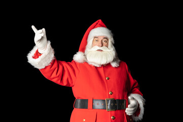 Santa Claus pointing at blank billboard isolated on black background. Santa is calling for Copyspace.