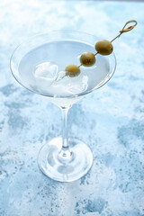 Glass of fresh martini on color background