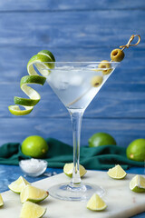 Glass of fresh martini on color background