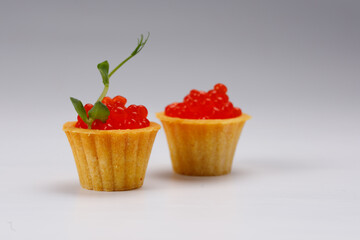 Appetizing tartlets with red caviar on a white plate. Holiday concept. Close-up.
