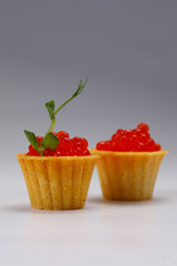 Appetizing tartlets with red caviar on a white plate. Holiday concept. Close-up.