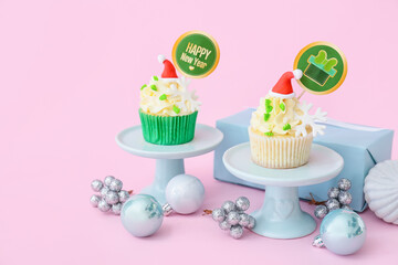 Dessert stand with tasty Christmas cupcakes on color background
