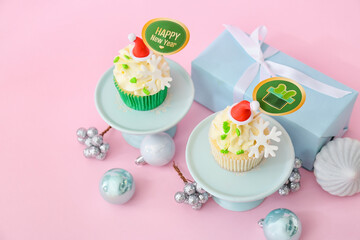 Dessert stand with tasty Christmas cupcakes on color background