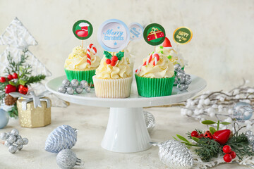 Dessert stand with tasty Christmas cupcakes on table