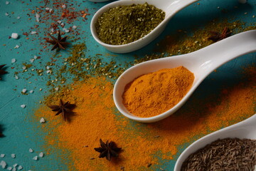 Various colorful herbs and spices for cooking in spoons. Pepper, chili, paprika, basil, turmeric.