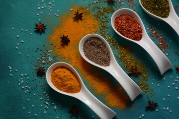 Various colorful herbs and spices for cooking in spoons. Pepper, chili, paprika, basil, turmeric.