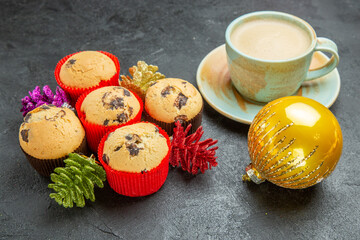 Obraz na płótnie Canvas Top view of freshly baked delicious cupcakes with a cup of coffee and colorful decorations on dark background
