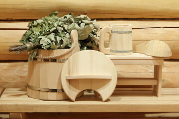 Wooden bucket, ladle and oak broom are on a bench in sauna.  