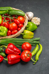Vertical view of fresh various organic vegetables in wicker basket on dark background