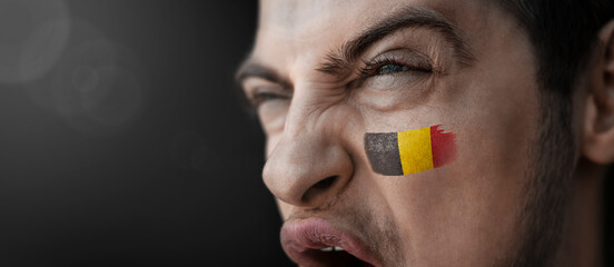 A screaming man with the image of the Belgium national flag on his face