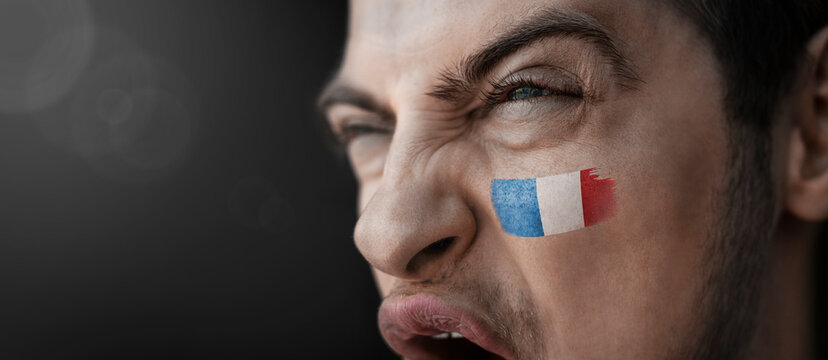 A screaming man with the image of the France national flag on his face