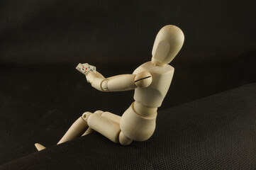 Mannequin holding playing cards isolated on a black background, gambling addiction concept