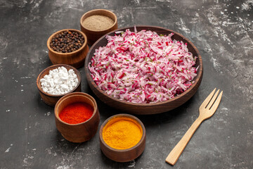 Side view of delicious vegetable salad with various ingredients in a brown bowl different spices and fork on dark background
