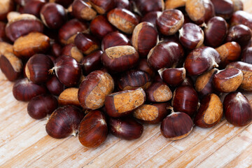Fototapeta premium Pile of unpeeled sweet chestnuts on wooden table