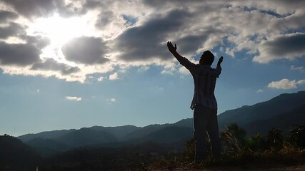 A man with hands raised standing on a mountaintop