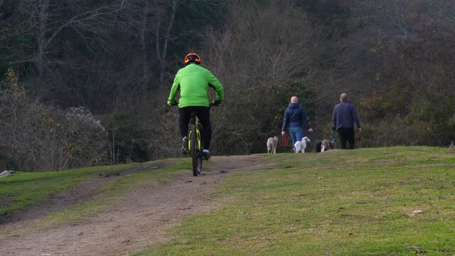 Ciclista in bicicletta nel parco del Sorbo, 
sullo sfondo due uomini con cane che passeggiano