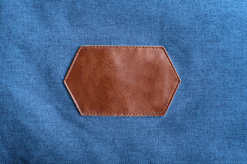 Brown leather label with stitching on denim fabric. Copy space. Mockup