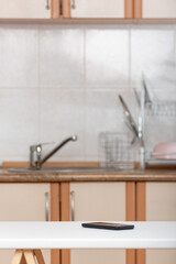 Forgotten smartphone on kitchen table. Mobile phone on the kitchen